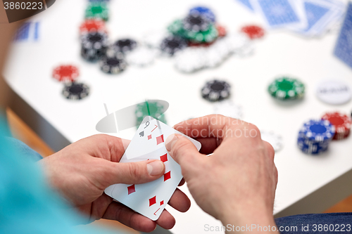 Image of close up of male hand with playing cards and chips