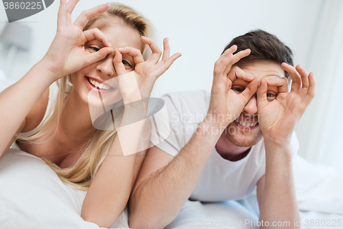 Image of happy couple lying in bed at home