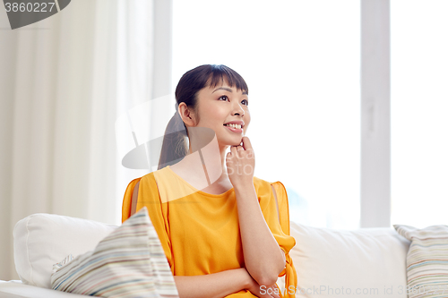 Image of happy asian young dreaming woman at home