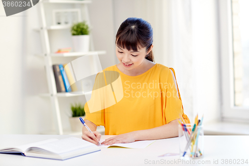 Image of happy asian young woman student learning at home