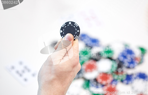 Image of close up of male hand holding casino chip