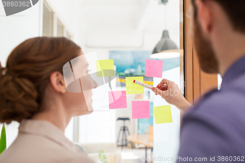 Image of creative team with stickers on glass at office