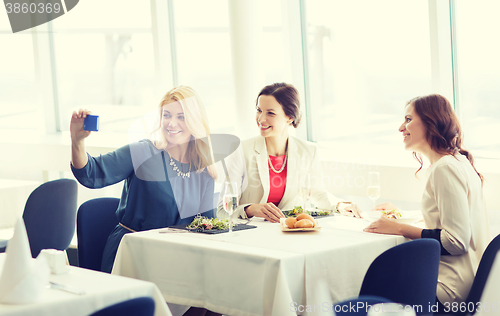 Image of women with smartphone taking selfie at restaurant