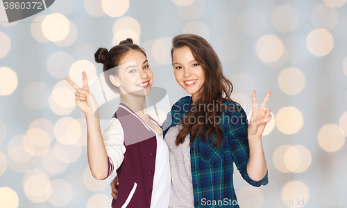 Image of happy teenage girls hugging and showing peace sign