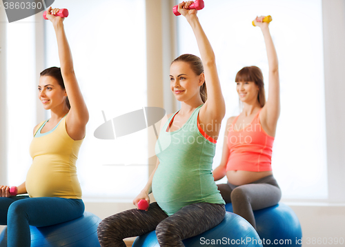 Image of happy pregnant women exercising on fitball in gym