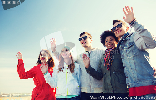 Image of happy teenage friends in shades waving hands