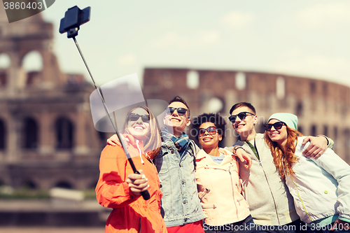Image of happy friends with smartphone selfie stick