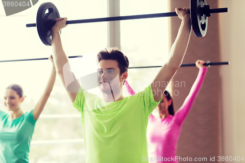 Image of group of people exercising with barbell in gym