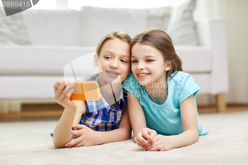 Image of happy girls with smartphone taking selfie at home