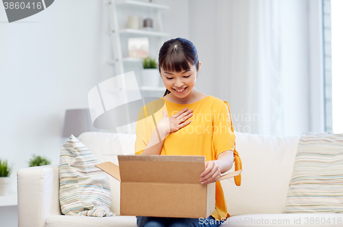 Image of happy asian young woman with parcel box at home