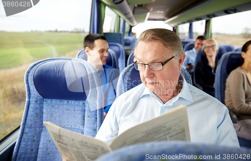 Image of happy senior man reading newspaper in travel bus