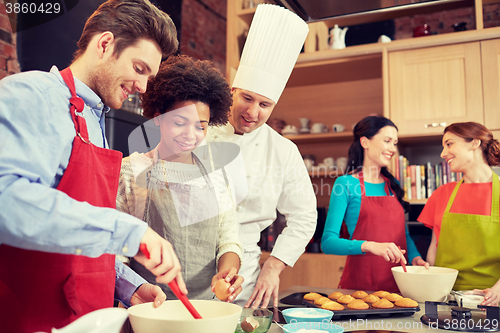 Image of happy friends and chef cook baking in kitchen