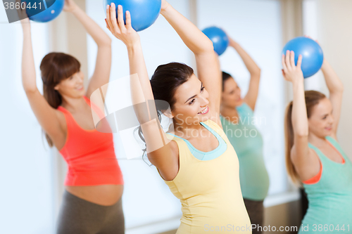 Image of happy pregnant women exercising with ball in gym