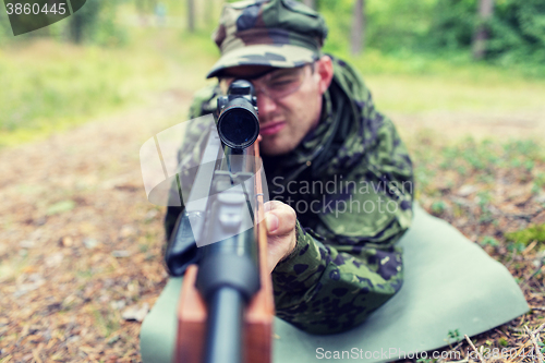 Image of close up of soldier or hunter with gun in forest