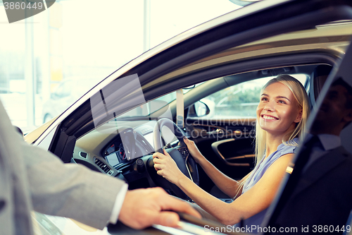 Image of happy woman with car dealer in auto show or salon