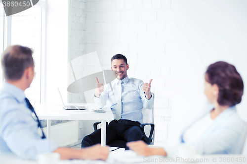 Image of businessman showing thumbs up in office