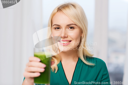 Image of smiling woman drinking juice or smoothie at home