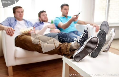 Image of close up of male friends watching tv at home