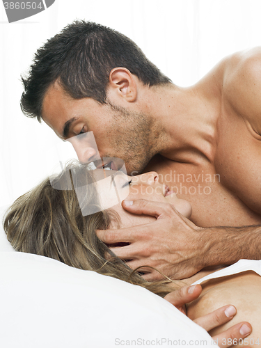 Image of man kissing his partner sweetly in white bed