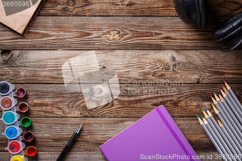 Image of Watercolors, color pencils and sketchbook on wooden table. Flat lay photo with empty space for logo, text.
