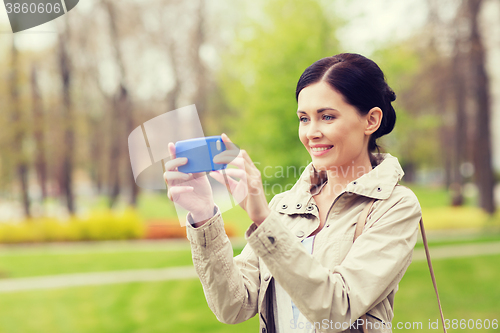 Image of smiling woman taking picture with smartphone