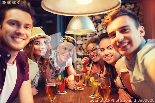 Image of happy friends with smartphone taking selfie at bar