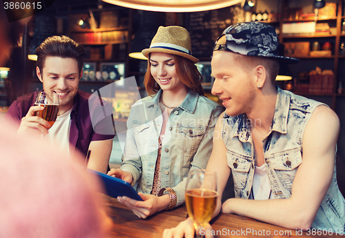 Image of happy friends with tablet pc and drinks at bar