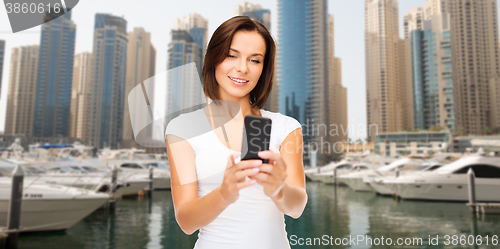 Image of woman taking selfie by smartphone over dubai city