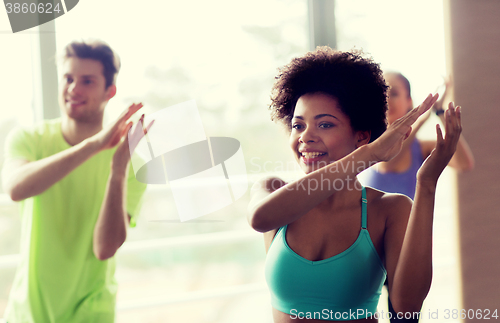 Image of group of smiling people dancing in gym or studio