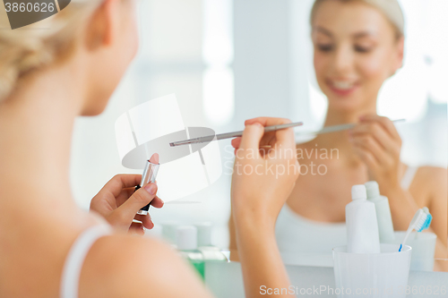 Image of woman with lipstick and make up brush at bathroom