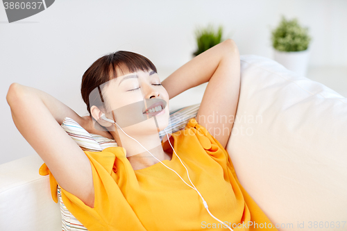 Image of happy asian woman with earphones listening music