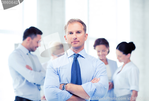 Image of handsome businessman with team in office