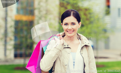 Image of smiling woman with shopping bags coming from sale