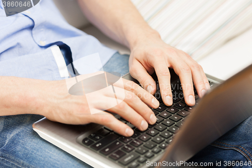 Image of close up of man typing on laptop computer at home