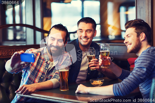 Image of friends taking selfie and drinking beer at bar