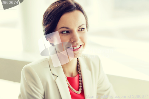 Image of happy elegant young woman in jacket at office
