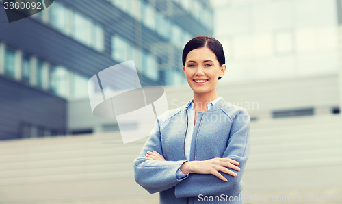 Image of young smiling businesswoman over office building