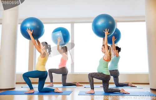 Image of happy pregnant women exercising with ball in gym