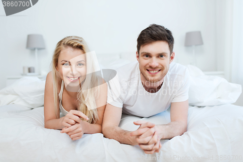 Image of happy couple lying in bed at home