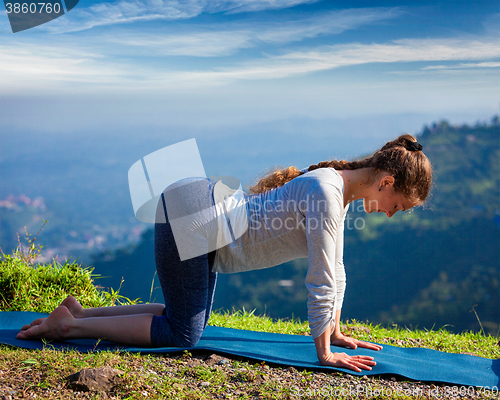 Image of Sporty fit woman practices yoga asana bitilasana outdoors