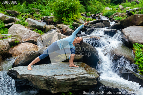 Image of Woman practices yoga asana Utthita Parsvakonasana outdoors