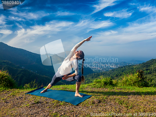 Image of Woman practices yoga asana Utthita Parsvakonasana outdoors