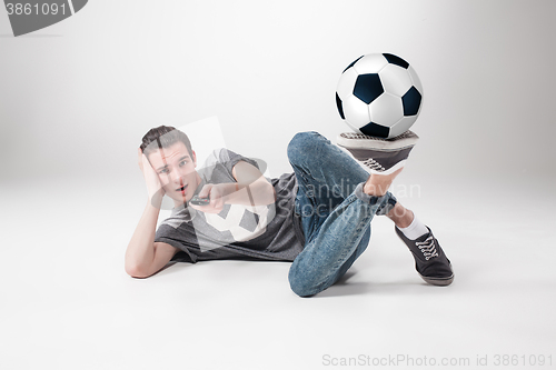 Image of The portrait of fan with ball, holding  tv remote on white background