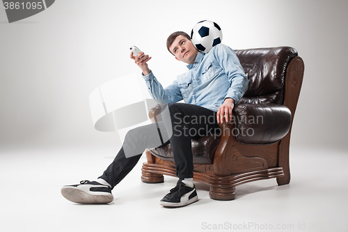 Image of The portrait of fan with ball, holding  tv remote on white background