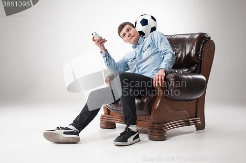 Image of The portrait of fan with ball, holding  tv remote on white background