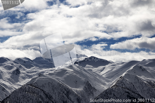 Image of View on snowy mountains and cloudy sky at evening