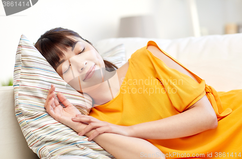 Image of happy asian teenage girl sleeping on sofa at home