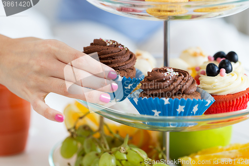 Image of close up of hand taking cupcake from cake stand