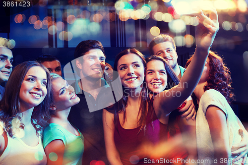 Image of friends with smartphone taking selfie in club