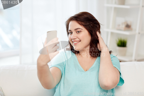 Image of happy plus size woman with smartphone at home